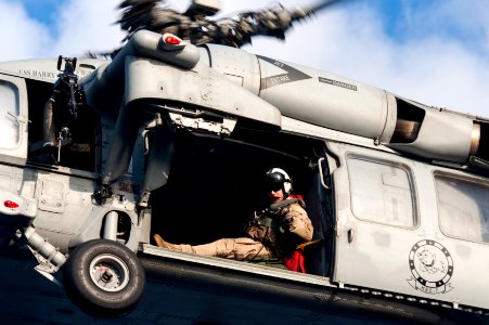 U.S. Navy Naval Aircrewman (Helicopter) 2nd Class Joseph Southern, assigned to Helicopter Sea Combat Squadron (HSC) 7, directs an MH-60S Seahawk helicopter as it lowers cargo to the flight deck of the aircraft 140307-N-ZG705-181