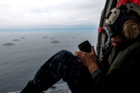 U.S. Navy Mass Communication Specialist 2nd Class Jonathan Colon prepares to take photos of the amphibious assault ship USS America (LHA 6) and Peruvian Navy ships as they sail in formation during a passing 140903-N-MZ309-1171