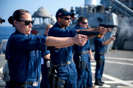 U.S. Navy Master-at-Arms 1st Class Krystal Meza, left, and Gunner's Mate 2nd Class Gregory Spaulding fire 9 mm pistols during a small-arms qualification aboard the guided missile destroyer USS Stout (DDG 55) 140118-N-UD469-492