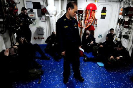 U.S. Navy Chief Electrician's Mate Hilario Gudez observes Sailors dawning their gas masks during a simulated chemical, biological, radiological attack scenario aboard the amphibious dock landing ship USS 110314-N-RC734-028