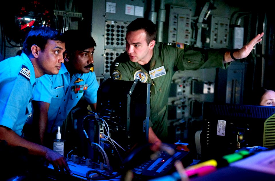 U.S. Navy Lt. Dan Mitzner discusses combat direction center operations with Cmdr. Ajay Daniel Theophilus and Lt. Cmdr. Madhavdas Ravikant of the Indian Navy aboard the USS Carl Vinson