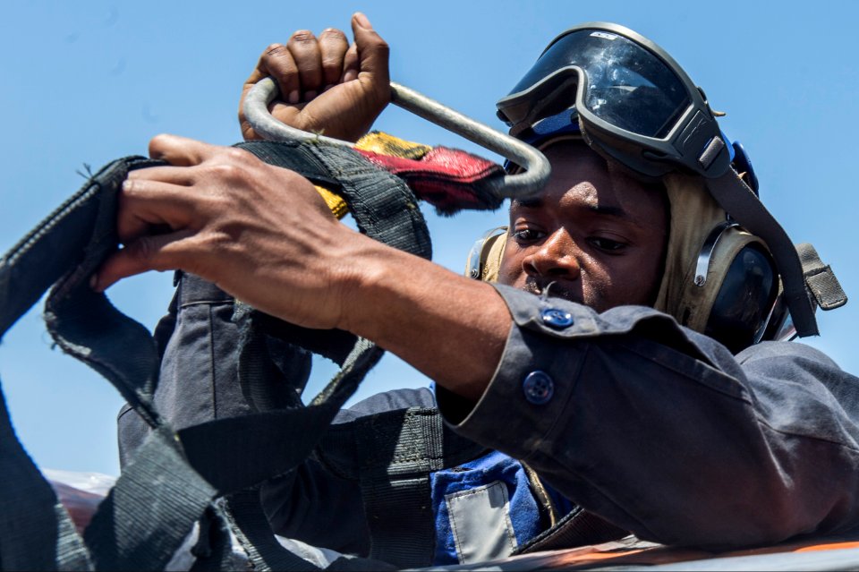 U.S. Navy Seaman Isaac Kinder removes a cargo net during a vertical replenishment aboard the guided missile cruiser USS Philippine Sea (CG 58) in the Arabian Sea April 9, 2014 140409-N-PJ969-114