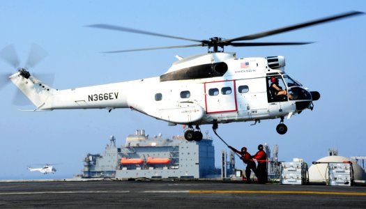 U.S. Sailors aboard the aircraft carrier USS George H.W. Bush (CVN 77) attach a cargo hook to a Military Sealift Command SA-330J Puma helicopter during a replenishment at sea with the dry cargo and ammunition 140827-N-CZ979-016