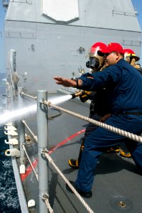 U.S. Navy Culinary Specialist 1st Class Eber Barraza provides fire hose training during a drill aboard the guided missile cruiser USS Philippine Sea (CG 58) in the Arabian Sea April 5, 2014 140405-N-PJ969-257