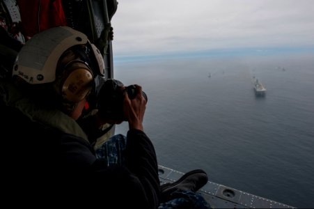 U.S. Navy Mass Communication Specialist 2nd Class Jonathan Colon takes photos of the amphibious assault ship USS America (LHA 6), left, and Peruvian Navy ships as they sail in formation during a passing exercise 140903-N-MZ309-1241