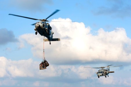 U.S. Navy MH-60S Seahawk helicopters assigned to Helicopter Sea Combat Squadron (HSC) 22, left, and HSC-7 deliver cargo to the aircraft carrier USS Harry S. Truman (CVN 75) during a replenishment at sea March 7 140307-N-ZG705-203