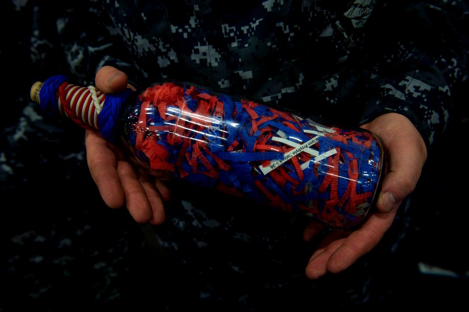 U.S. Navy Operations Specialist 1st Class Steven Lowe, selected for promotion to chief petty officer, holds one of three bottles containing the names of Sept 140911-N-MD297-009