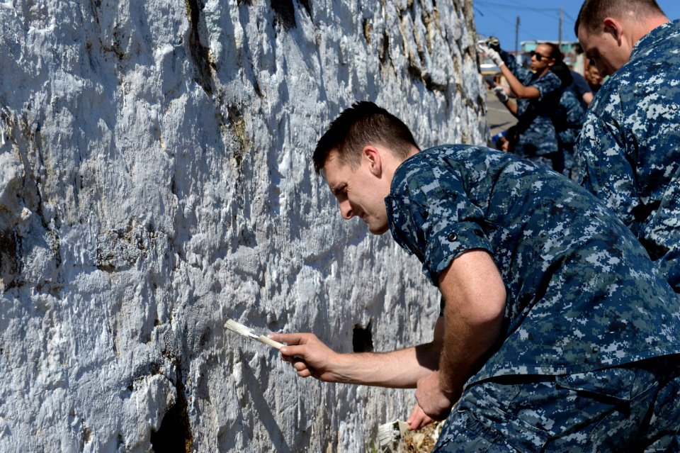 U.S. Navy Fire Controlman 2nd Class Patrick Caldwell, assigned to the newly commissioned amphibious assault ship USS America (LHA 6), paints an exterior wall at a children's home in Valparaiso, Chile, Aug. 26 140826-N-MZ309-082