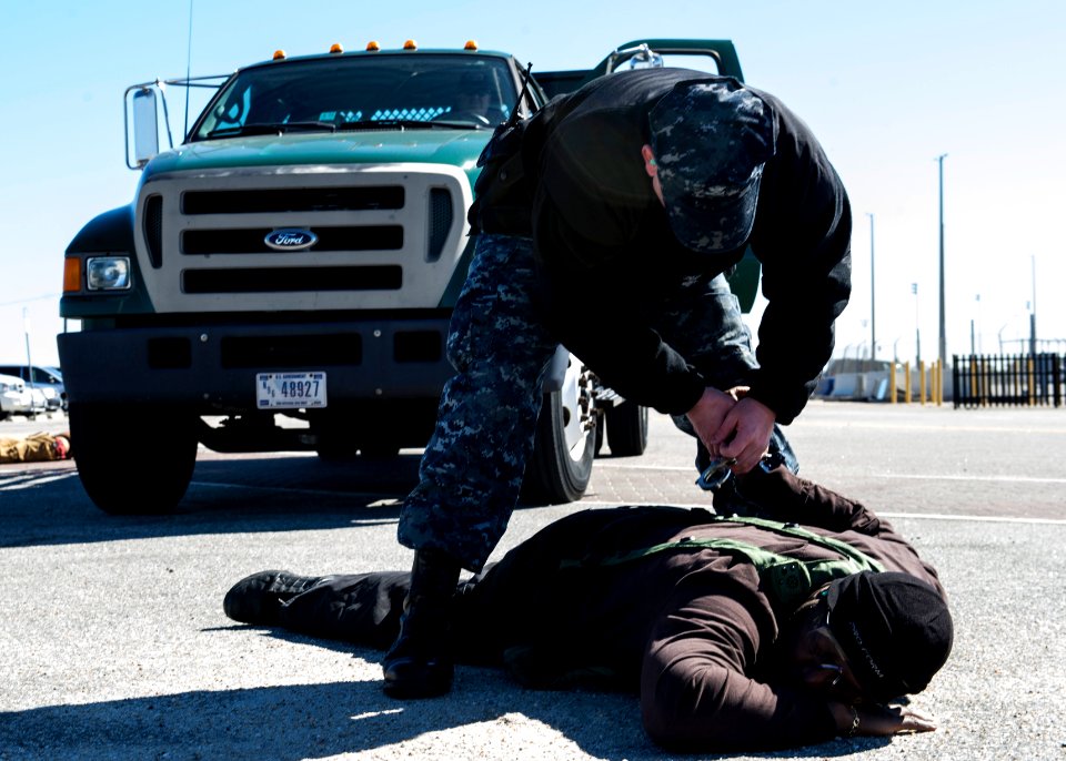 U.S. Navy Master-at-Arms 2nd Class Robert Heckerman, standing, subdues Charles Streat after disarming him Feb. 27, 2014, during a vehicle-borne improvised explosive device response exercise as part of Solid 140227-N-XQ474-096