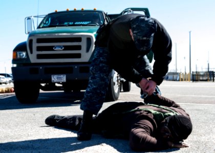 U.S. Navy Master-at-Arms 2nd Class Robert Heckerman, standing, subdues Charles Streat after disarming him Feb. 27, 2014, during a vehicle-borne improvised explosive device response exercise as part of Solid 140227-N-XQ474-096