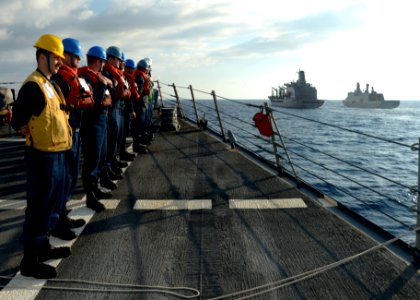 U.S. Sailors assigned to the guided missile destroyer USS Ramage (DDG 61) stand in formation as the ship makes its approach alongside the fleet replenishment oiler USNS John Lenthall (T-AO 189), center, to 140326-N-CH661-003