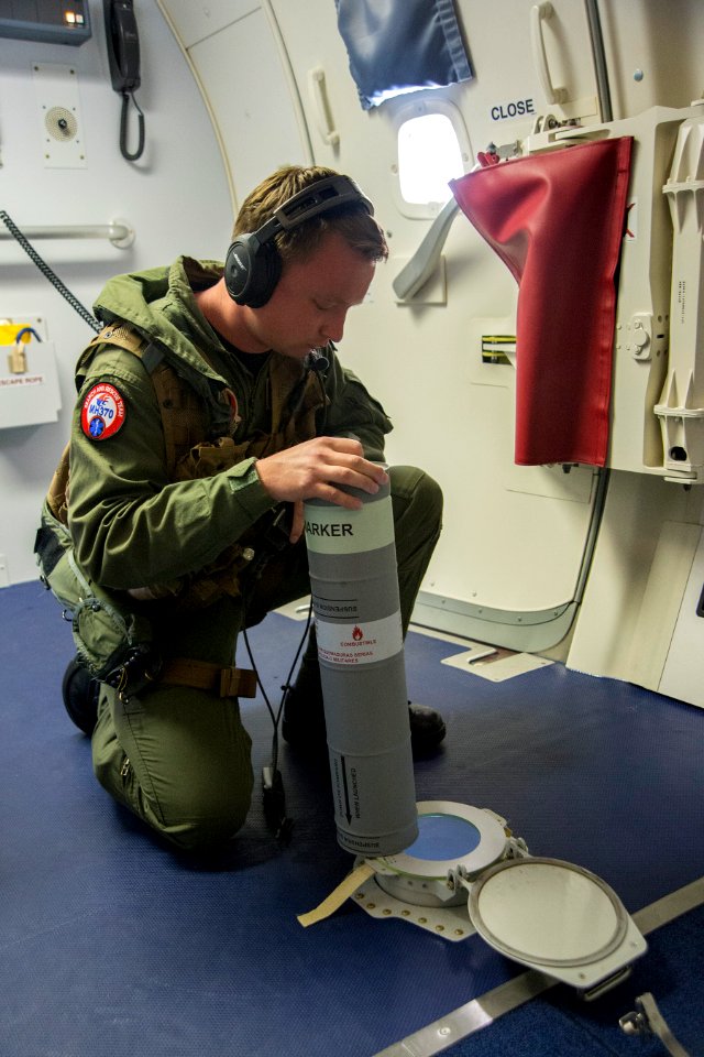 U.S. Navy Naval Aircrewman (Operator) 2nd Class Clark Urbin, assigned to Patrol Squadron (VP) 16, prepares to deploy a Mark 58 marine location marker out of the freefall chute of a P-8A Poseidon aircraft while 140415-N-VD564-020