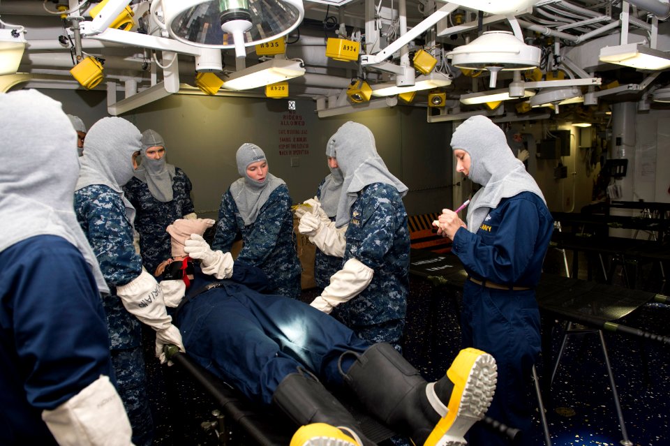 U.S. Sailors assigned to the medical department aboard the amphibious assault ship USS America (LHA 6) examine a simulated victim during a general quarters drill Sept 140906-N-MD297-043
