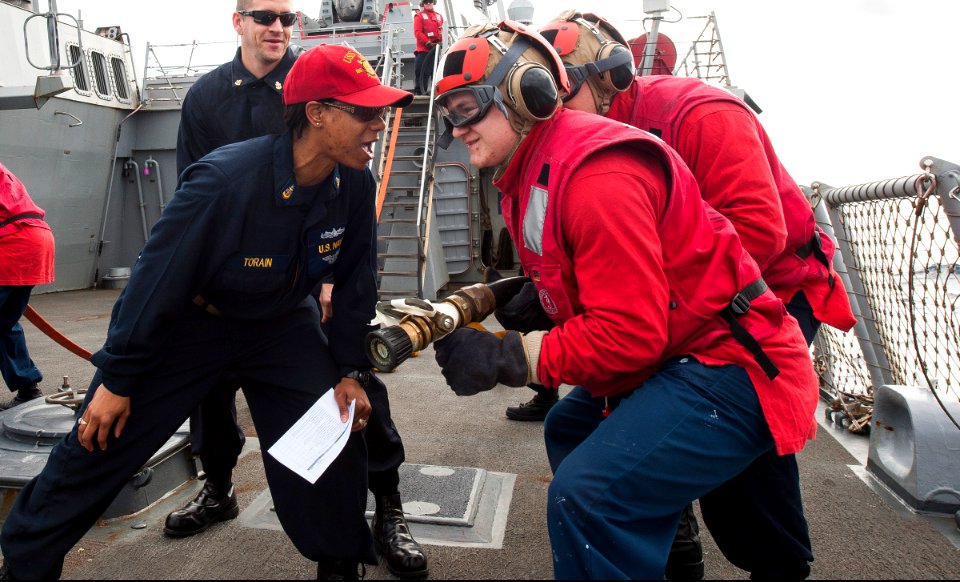 U.S. Navy Senior Chief Damage Controlman Lavoskia Torain, front left, gives instructions to Sailors during a damage control training drill on the flight deck of the guided missile destroyer USS Ross (DDG 71) 140317-N-WX580-037