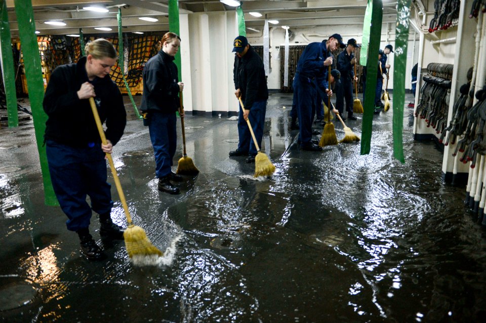 U.S. Sailors aboard the amphibious transport dock ship USS Mesa Verde (LPD 19) sweep away water after a test of aqueous film-forming foam stations during the ship's Board of Inspection and Survey (INSURV) 140116-N-BD629-368