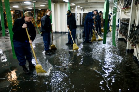 U.S. Sailors aboard the amphibious transport dock ship USS Mesa Verde (LPD 19) sweep away water after a test of aqueous film-forming foam stations during the ship's Board of Inspection and Survey (INSURV) 140116-N-BD629-368