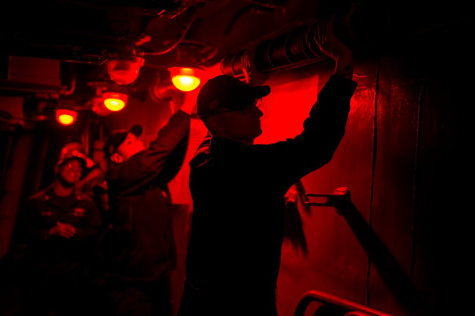 U.S. Navy Sonar Technician 2nd Class Bryon Altenbach, right, and Fire Controlman 3rd Class Lance Simon remove the flag staff from the port break aboard the guided missile destroyer USS Stout (DDG 55) in 140119-N-UD469-003