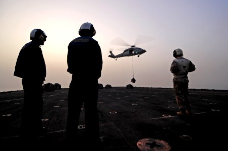 U.S. Sailors stand by for supplies as a MH-60S Seahawk helicopter, assigned to Helicopter Sea Combat Squadron (HSC) 26, delivers cargo to amphibious dock landing ship USS Comstock (LSD 45) during a vertical 110717-N-RC734-328