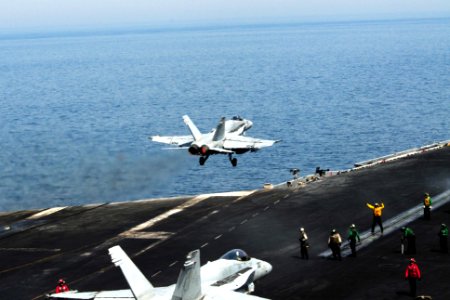 U.S. Sailors prepare to launch an F-A-18C Hornet aircraft attached to Strike Fighter Squadron (VFA) 15 as an F-A-18C Hornet aircraft takes off from the aircraft carrier USS George H.W. Bush (CVN 77) in 140630-N-CZ979-014