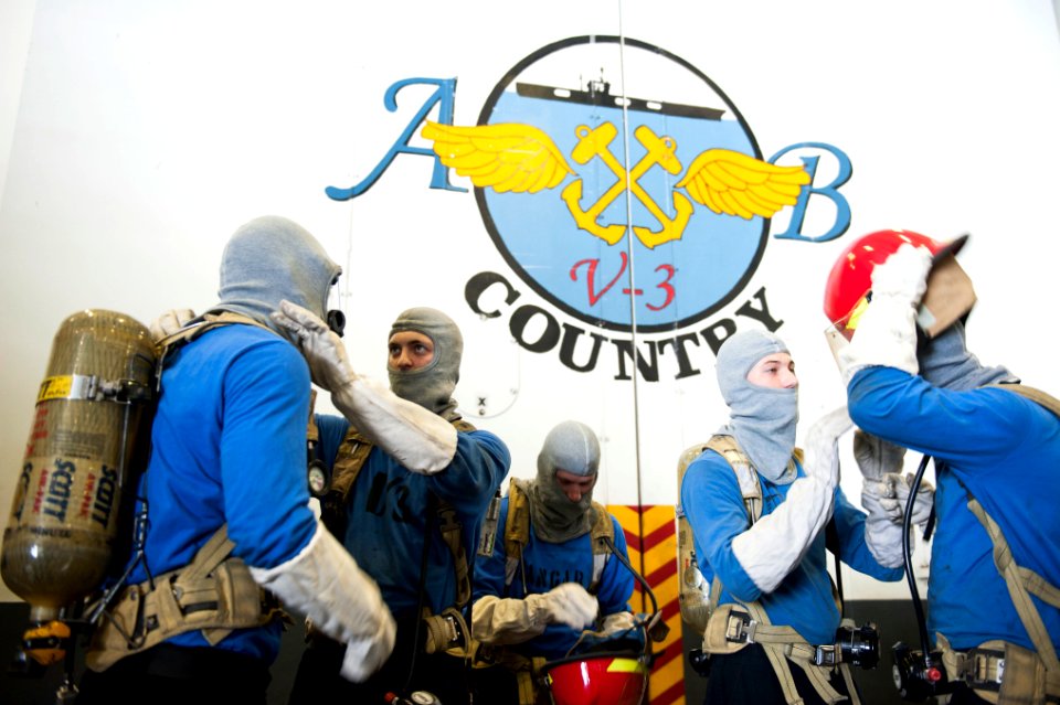 U.S. Sailors don firefighting gear before a general quarters drill in the hangar bay of the aircraft carrier USS Harry S. Truman (CVN 75) March 8, 2014, in the Gulf of Oman 140308-N-ZG705-252
