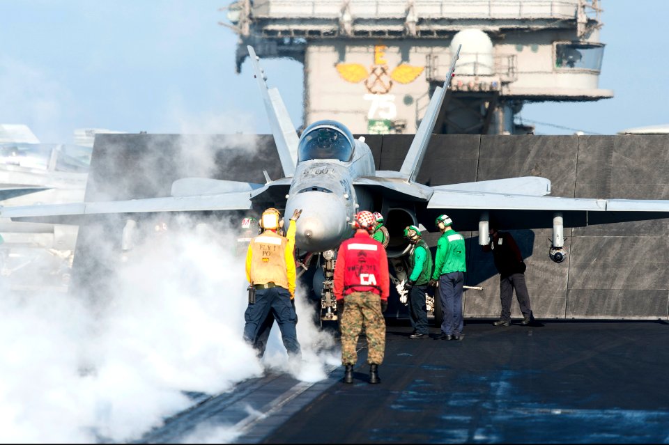 U.S. Sailors and Marines guide an F-A-18C Hornet aircraft assigned to Marine Fighter Attack Squadron (VMFA) 312 onto a catapult on the flight deck of the aircraft carrier USS Harry S. Truman (CVN 75) March 8 140308-N-ZG705-060
