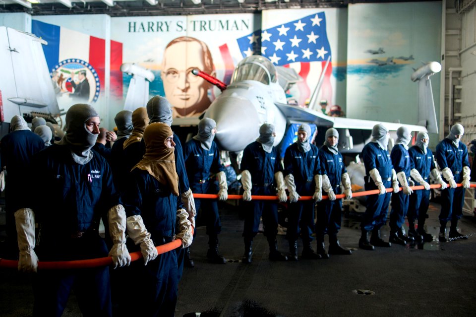 U.S. Sailors man a hose during a general quarters drill in the hangar bay of the aircraft carrier USS Harry S. Truman (CVN 75) in the Persian Gulf Jan. 17, 2014 140117-N-ZG705-241