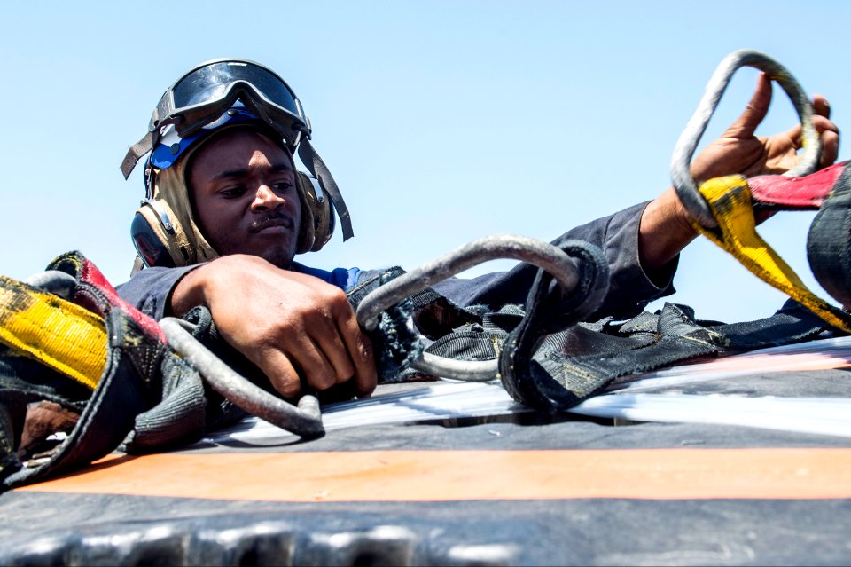 U.S. Navy Seaman Isaac Kinder removes a cargo net during a vertical replenishment aboard the guided missile cruiser USS Philippine Sea (CG 58) in the Arabian Sea April 9, 2014 140409-N-PJ969-112