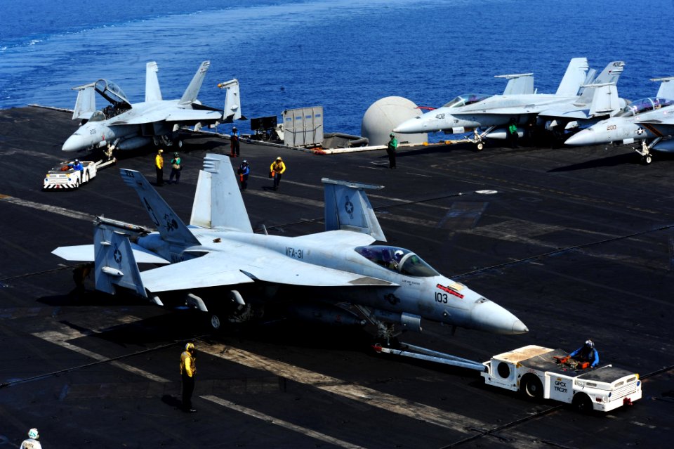 U.S. Sailors move a Navy F-A-18E Super Hornet aircraft assigned to Strike Fighter Squadron (VFA) 31 on the flight deck of the aircraft carrier USS George H.W. Bush (CVN 77) Aug. 26, 2014, in the Persian Gulf as 140826-N-CZ979-006