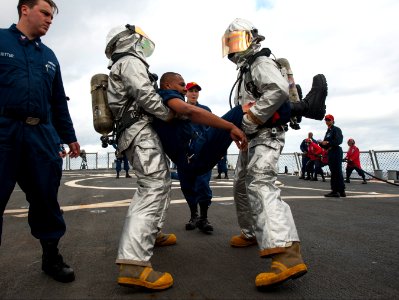 U.S. Sailors wearing firefighting proximity suits carry a simulated casualty during a damage control training drill on the flight deck of the guided missile destroyer USS Ross (DDG 71) in the Atlantic Ocean 140317-N-WX580-065