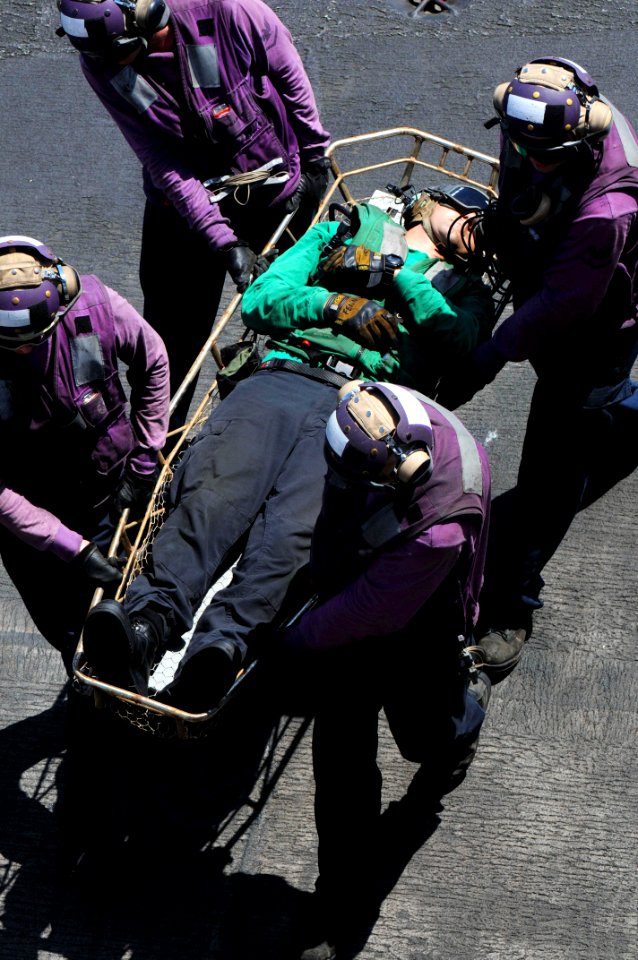U.S. Sailors transport a wounded Sailor to the medical department June 27, 2014, during a general quarters drill on the flight deck of the aircraft carrier USS George H.W. Bush (CVN 77) in the Persian Gulf 140627-N-CZ979-071