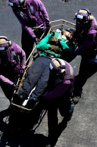 U.S. Sailors transport a wounded Sailor to the medical department June 27, 2014, during a general quarters drill on the flight deck of the aircraft carrier USS George H.W. Bush (CVN 77) in the Persian Gulf 140627-N-CZ979-071
