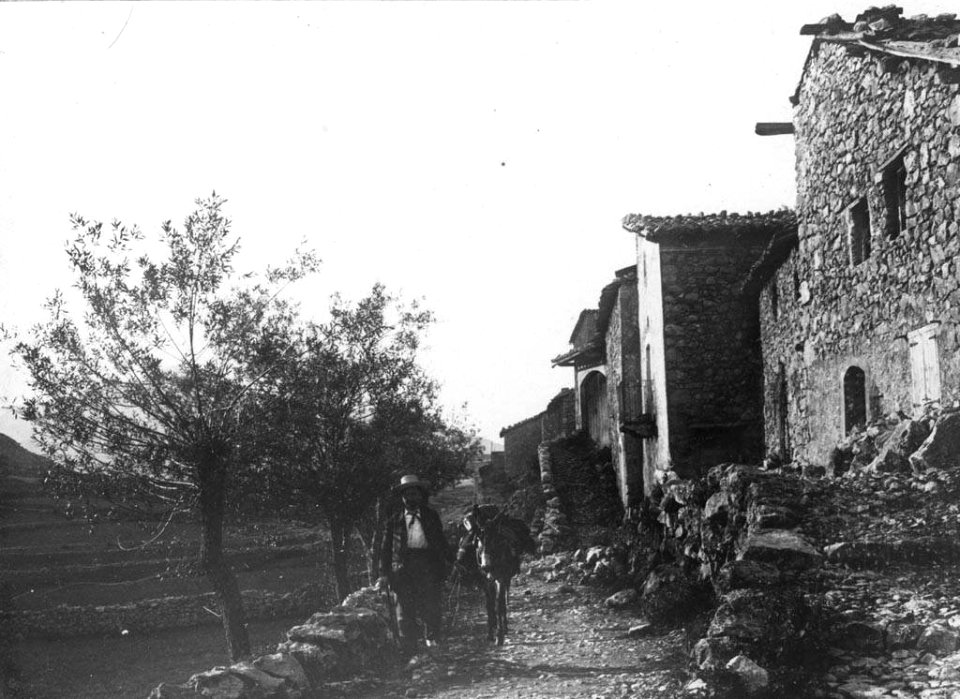 Un home amb un ase en un carrer d'un poble