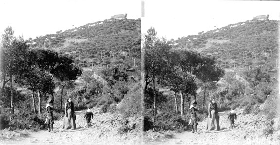 Una dona i dos nens en un camí voltat de bosc a la Rabassada , al fons un edifici