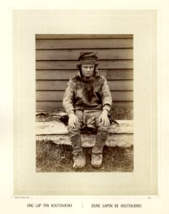 Ung same fra Kautokeino med sitter på en benk utenfor bygning - Norsk folkemuseum - NF.15006-035