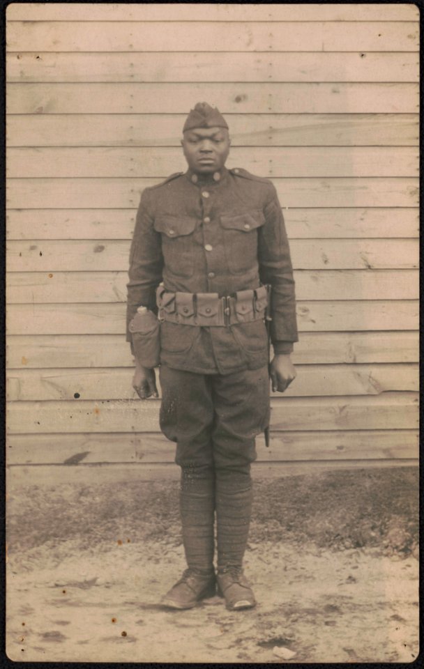 Unidentified African American soldier in uniform and overseas cap with canteen and knife hanging from cartridge belt LCCN2017648674