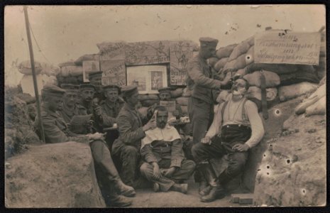 Unidentified German soldiers, some in uniform, seated in trench reading as two get a haircut and shave LCCN2018646047