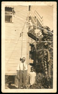 Unidentified man and girl standing in front of a dwelling with a fire escape LCCN2015652134