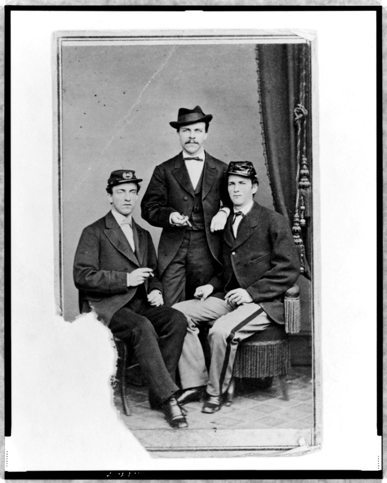Unidentified group of three men, full-length portrait, two seated, one standing in the background, facing front LCCN98506734