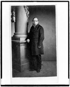 Unidentified man, full-length portrait, wearing spectacles with colored lenses, standing next to column, facing left LCCN98506729