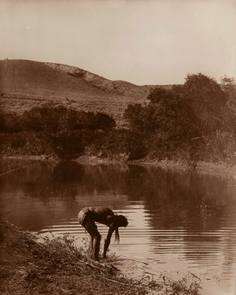 Untitled (Native American bending at riverbank)