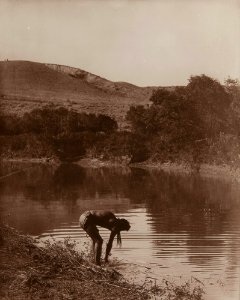 Untitled (Native American bending at riverbank)