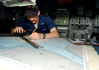 US Navy 020627-N-4374S-007 Quartermaster plots ship's position on the bridge
