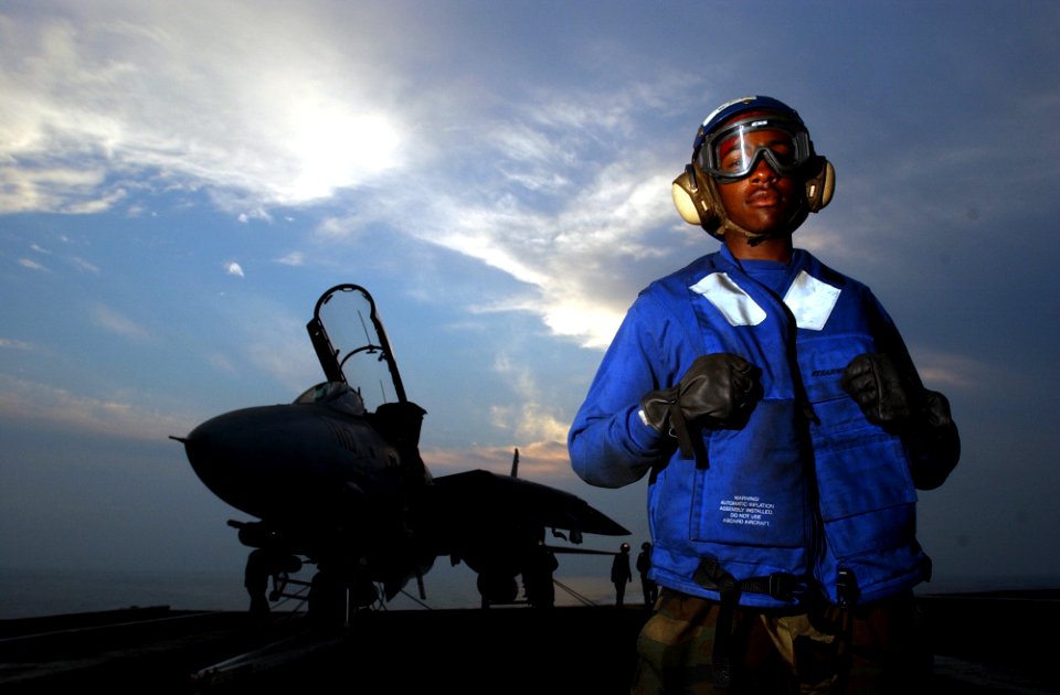 US Navy 021031-N-4309A-017 Flight deck crew aboard the nuclear powered aircraft carrier USS Abraham Lincoln (CVN 72), watches the sun set as they wait for night flight deck operations to begin