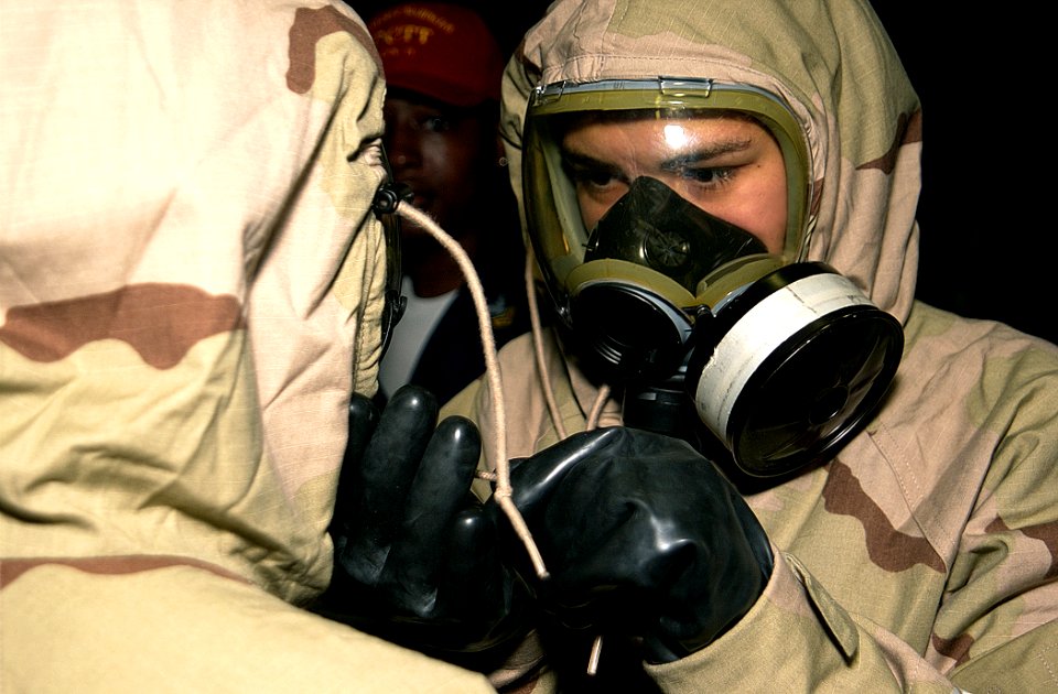US Navy 020928-N-2781V-028 Personnelman Seaman Sara Young adjusts her shipmate's protective suit during a chemical, biological, radiological (CBR) general quarters (GQ) drill