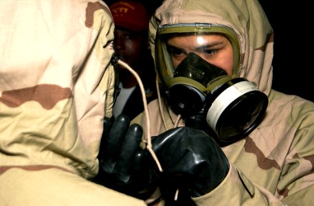US Navy 020928-N-2781V-028 Personnelman Seaman Sara Young adjusts her shipmate's protective suit during a chemical, biological, radiological (CBR) general quarters (GQ) drill