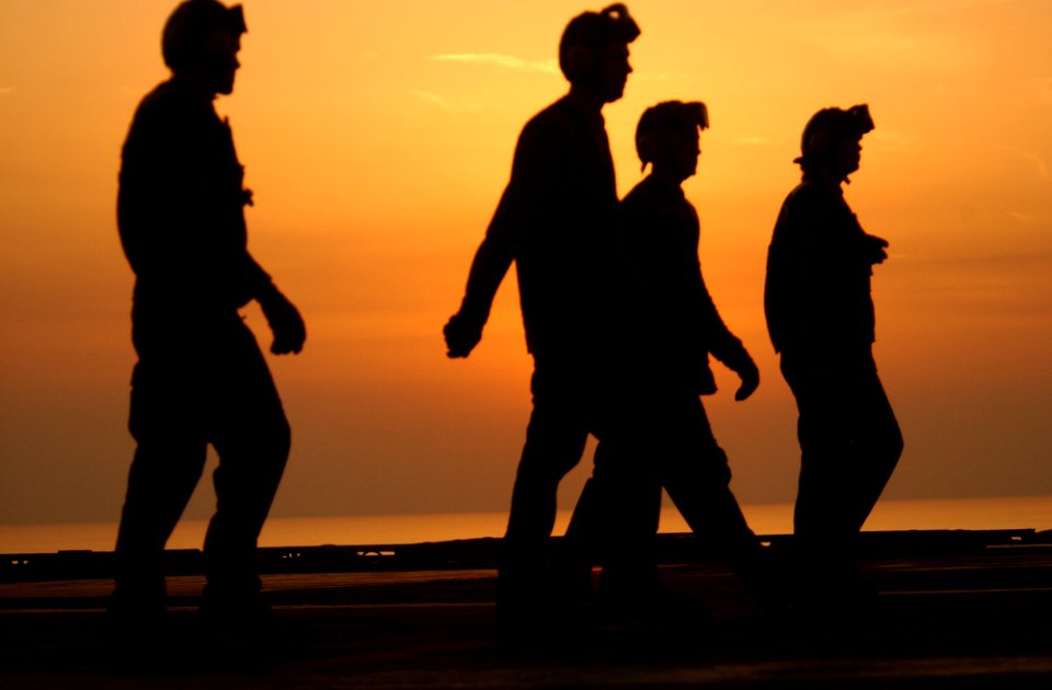 US Navy 021029-N-4309A-012 Crewmembers walk across the ship's flight deck before the sun sets over the Arabian Sea