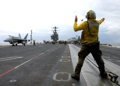 US Navy 021209-N-6895M-503 plane director guides an F-A-18 into position on the ship's flight deck