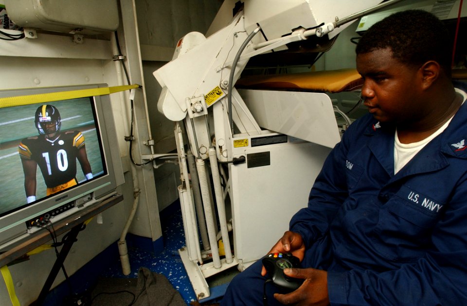 US Navy 021022-N-5471P-015 Ships Serviceman Third Class Sheikeil Odom relaxes after duty hours by playing a video game in his work space aboard the Mobile Bay