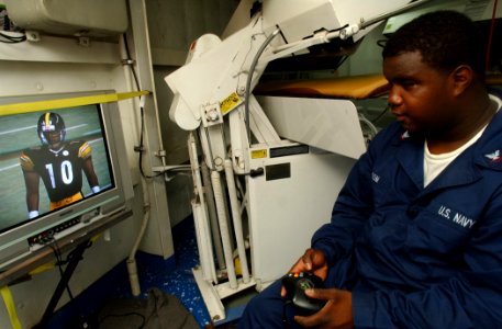US Navy 021022-N-5471P-015 Ships Serviceman Third Class Sheikeil Odom relaxes after duty hours by playing a video game in his work space aboard the Mobile Bay