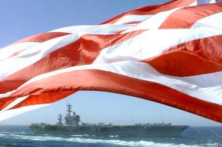 US Navy 020926-N-0000X-001 The USS Nimitz (CVN 68) steams alongside the Princeton as the American Flag waves proudly in the wind